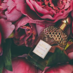 Luxurious perfume bottle nestled within vibrant pink peonies, showcasing elegance and beauty.